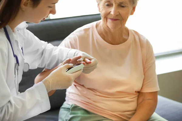 Doctor checking blood sugar level of diabetic woman at home — Stock Photo, Image