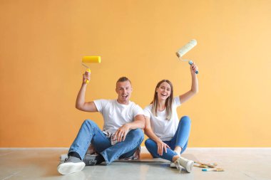 Yeni evlerinde yerde oturan boya silindirleri ile Mutlu genç çift