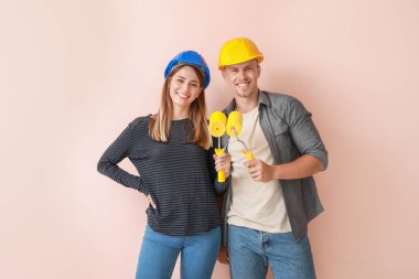 Renk arka plan üzerinde boya silindirleri ile Mutlu genç çift