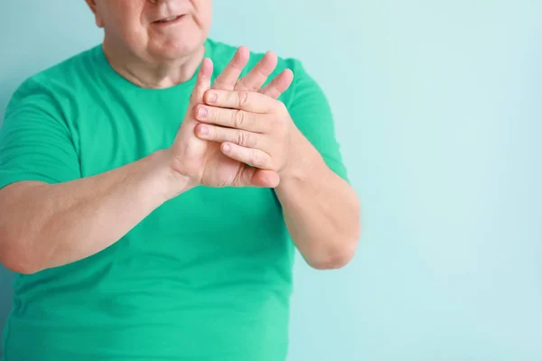 Senior man suffering from pain in wrist on light background — Stock Photo, Image