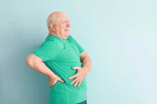 Senior leidet an Rückenschmerzen vor hellem Hintergrund — Stockfoto