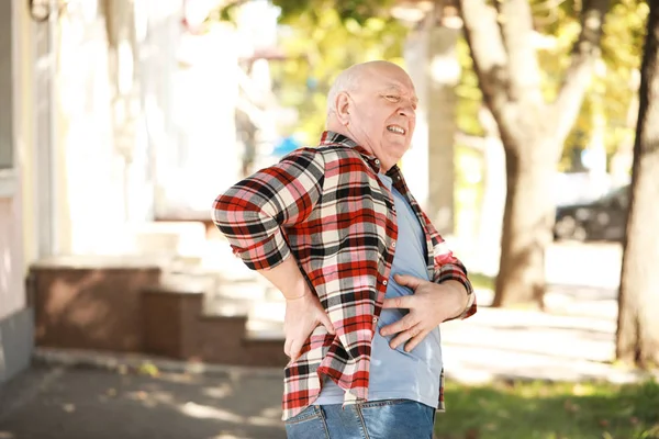 Senior man suffering from back pain outdoors — Stock Photo, Image