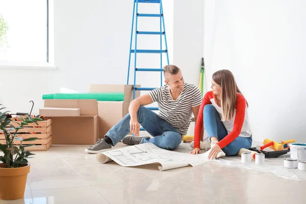 Feliz joven pareja planeando la reparación en su nueva casa — Foto de Stock