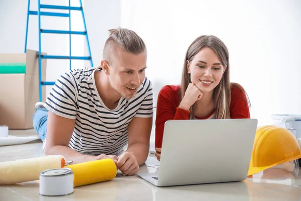 Yeni evlerinde dizüstü bilgisayar tamiratı yapan mutlu genç çift. — Stok fotoğraf