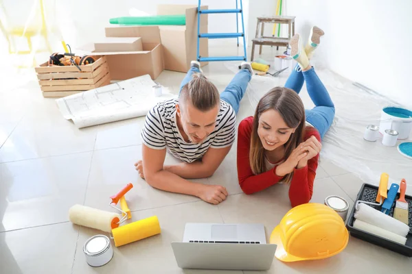 Yeni evlerinde dizüstü bilgisayar tamiratı yapan mutlu genç çift. — Stok fotoğraf