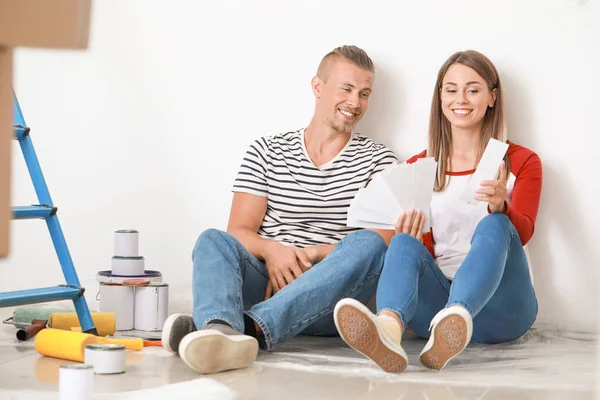 Casal jovem feliz escolhendo a cor de paredes em sua nova casa — Fotografia de Stock