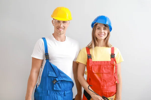 Glückliches junges Paar mit Werkzeugen auf hellem Hintergrund — Stockfoto
