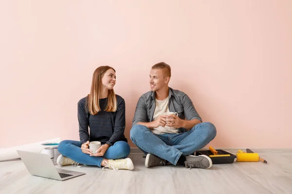 Happy young couple with laptop resting during repair in their new house — Stock Photo, Image