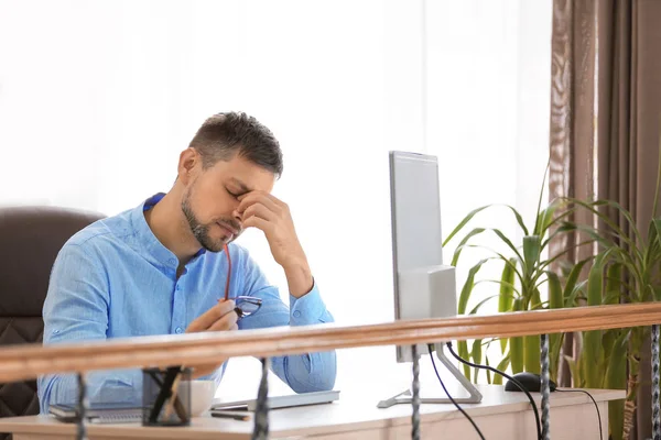 Vermoeide zakenman aan tafel in functie — Stockfoto