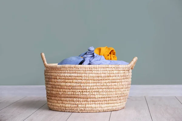 Basket with laundry on floor near grey wall