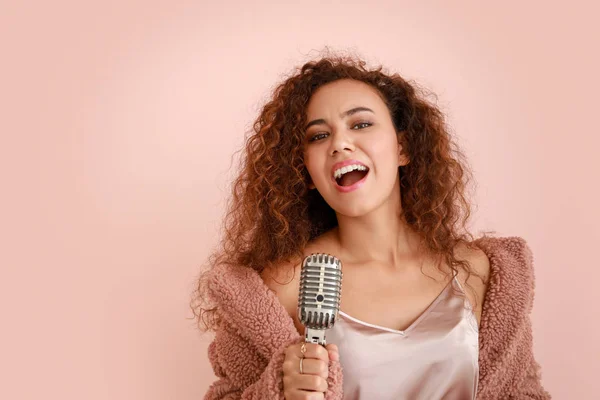 Belle chanteuse afro-américaine avec microphone sur fond de couleur — Photo