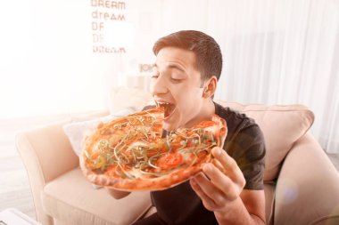 Genç adam evde lezzetli pizzalar yiyor.