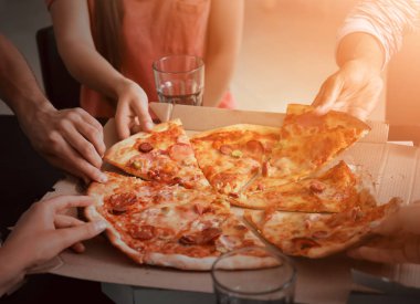 Genç insanlar sıcak lezzetli pizza dilimlerini karton kutu