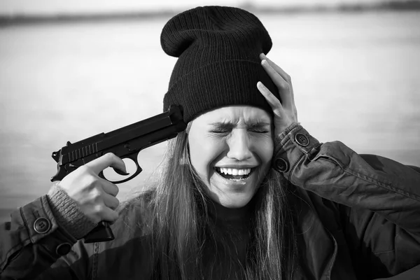 Black and white photo of young woman with gun is going to commit suicide outdoors — Stock Photo, Image