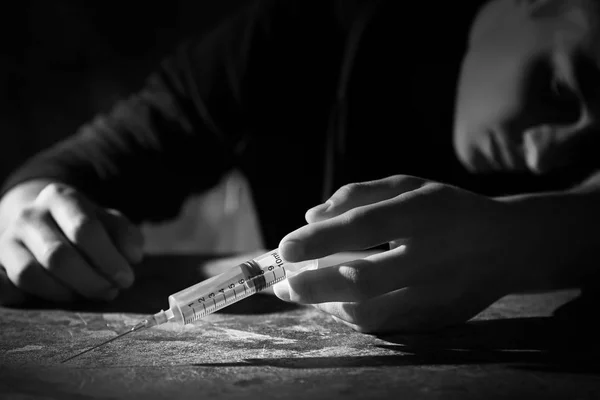 Photo noir et blanc de suicidaire masculin avec seringue à table — Photo