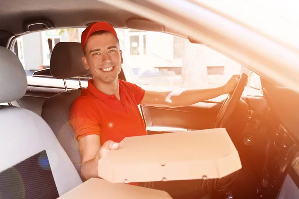 Delivery man with pizza box sitting in car