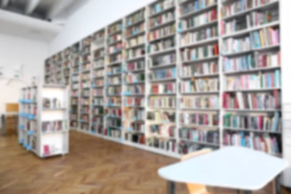 Muitos livros em prateleiras na biblioteca moderna, visão turva — Fotografia de Stock