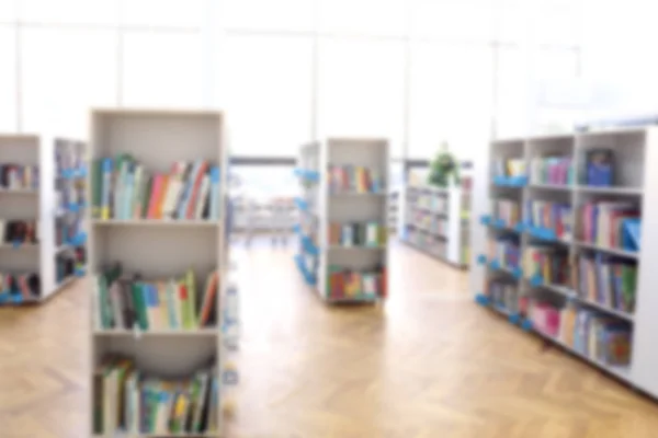 Veel boeken op de planken in moderne bibliotheek, wazig zicht — Stockfoto