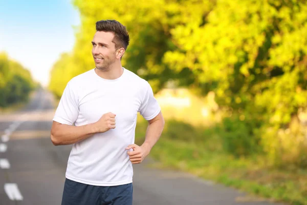 Sporty young man running outdoors — Stock Photo, Image