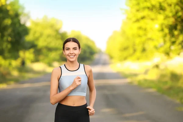 Sporty young woman running outdoors — Stock Photo, Image