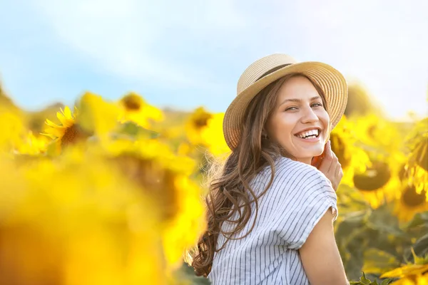 Beautiful young woman in sunflower field on summer day — Stock Photo, Image