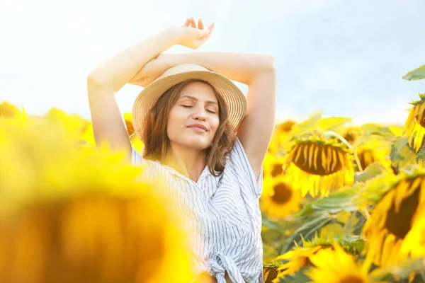 Beautiful young woman in sunflower field on summer day — Stock Photo, Image