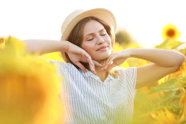 Beautiful young woman in sunflower field on summer day — Stock Photo, Image