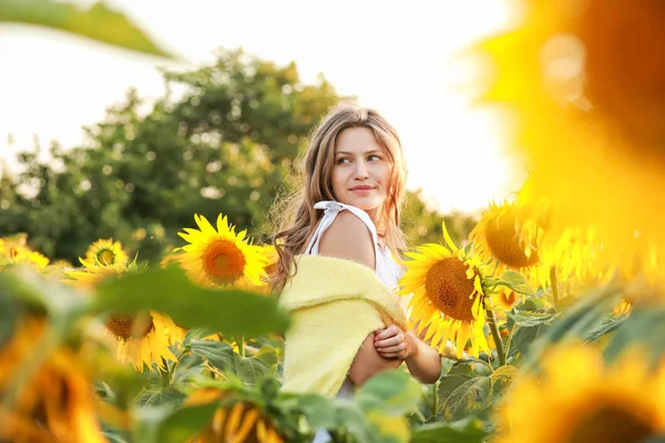 Beautiful young woman in sunflower field on summer day — Stock Photo, Image