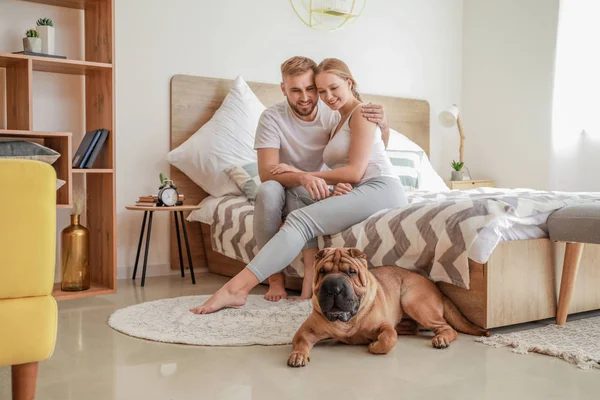 Cute Shar-Pei dog with owners in bedroom — Stock Photo, Image