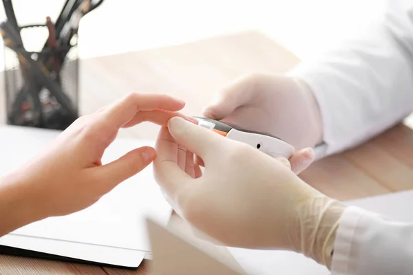 Ο γιατρός ελέγχει το επίπεδο του σακχάρου στο αίμα της διαβητικής γυναίκας στην κλινική, κοντινό — Φωτογραφία Αρχείου