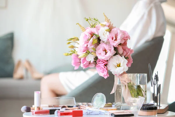 Belo buquê de casamento com cosméticos de maquiagem na mesa — Fotografia de Stock