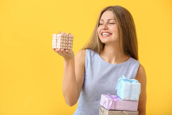 Beautiful young woman with gifts on color background — Stock Photo, Image