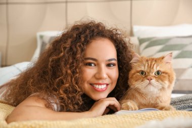 Evde sevimli kedi okuma kitabı ile Genç Afrikalı-Amerikalı kadın