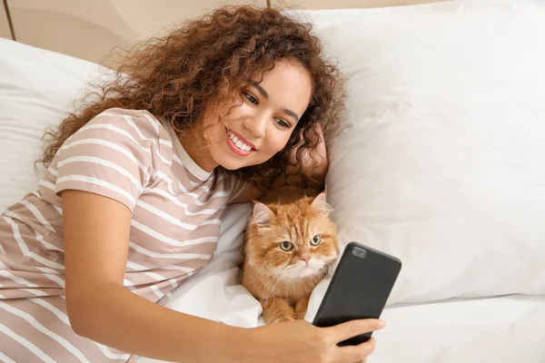 Young African-American woman with cute cat taking selfie at home — Stock Photo, Image