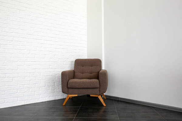 Stylish armchair near white brick wall in room