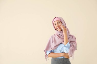 Güzel genç Müslüman kadın ışık arka plan üzerinde telefonla konuşuyor