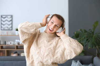 Evde müzik dinleyen güzel genç bir kadın.