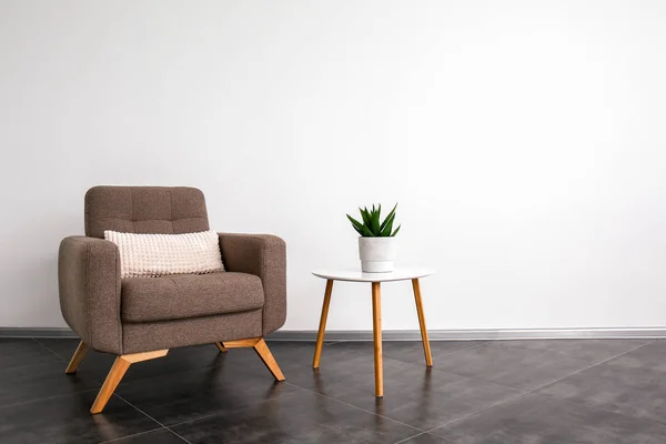 Comfortabele fauteuil en tafel in de buurt van lichte muur — Stockfoto