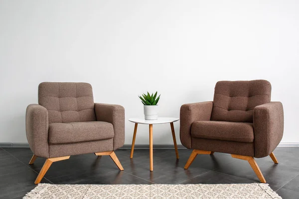 Cómodos sillones y mesa cerca de la pared de luz — Foto de Stock