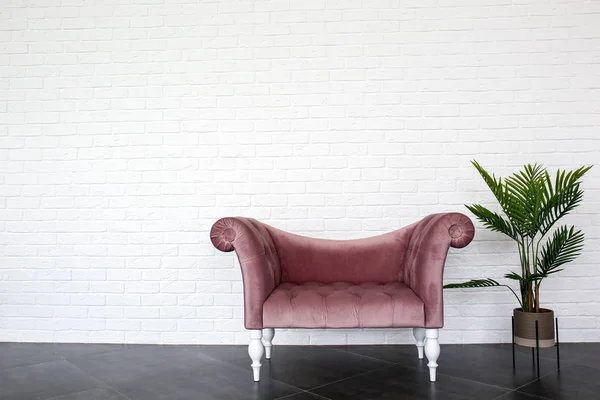 Comfortable sofa and houseplant near white brick wall — Stock Photo, Image