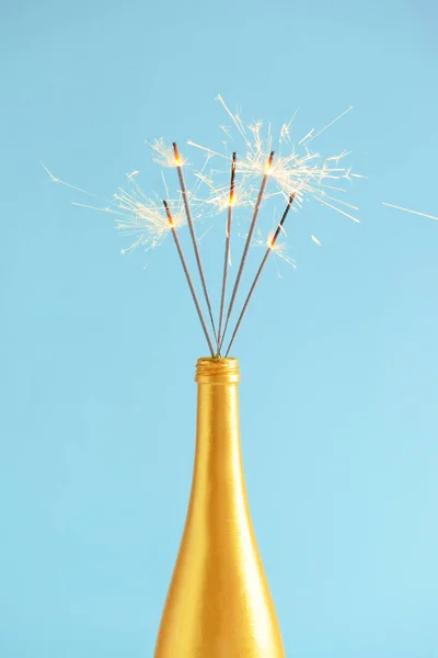 Bottle of champagne with festive Christmas sparklers on color background — Stock Photo, Image