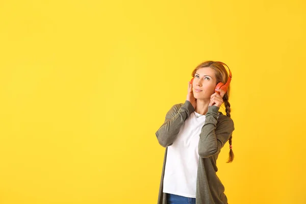 Beautiful young woman listening to music on color background — Stock Photo, Image