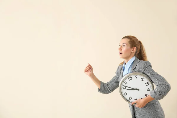 Laufende junge Geschäftsfrau mit Uhr auf hellem Hintergrund — Stockfoto