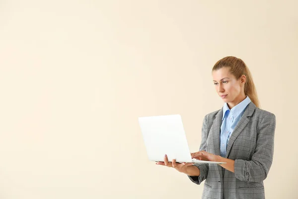 Mooie jonge zakenvrouw met laptop op lichte achtergrond — Stockfoto