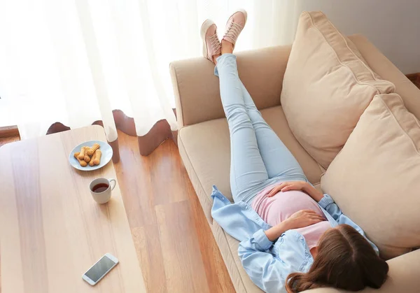 Bella donna incinta sdraiata sul divano a casa — Foto Stock