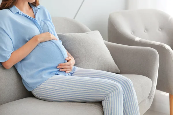 Beautiful pregnant woman sitting on sofa at home — Stock Photo, Image