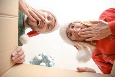 Noel Baba şapkalı mutlu çift Noel hediyesi açıyor, kutudan görünümü