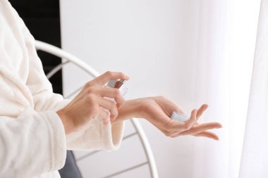 Evinde parfüm şişesi olan güzel genç bir kadın.