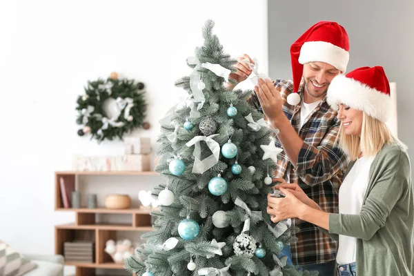 Happy couple decorating Christmas tree at home — Stock Photo, Image