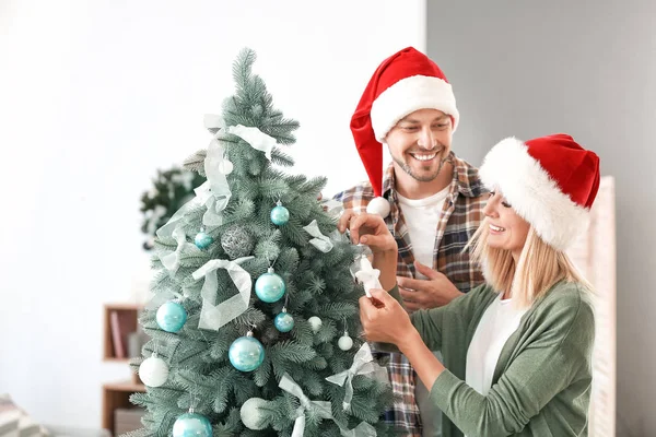 Happy couple decorating Christmas tree at home — Stock Photo, Image